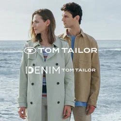 Hellgrüner Trenchcoat, beiges Hemd, weiße Hose und braune Schuhe. Beide Kleidungsstücke sind lässig, mit weichen Texturen vor einer felsigen Strandkulisse.