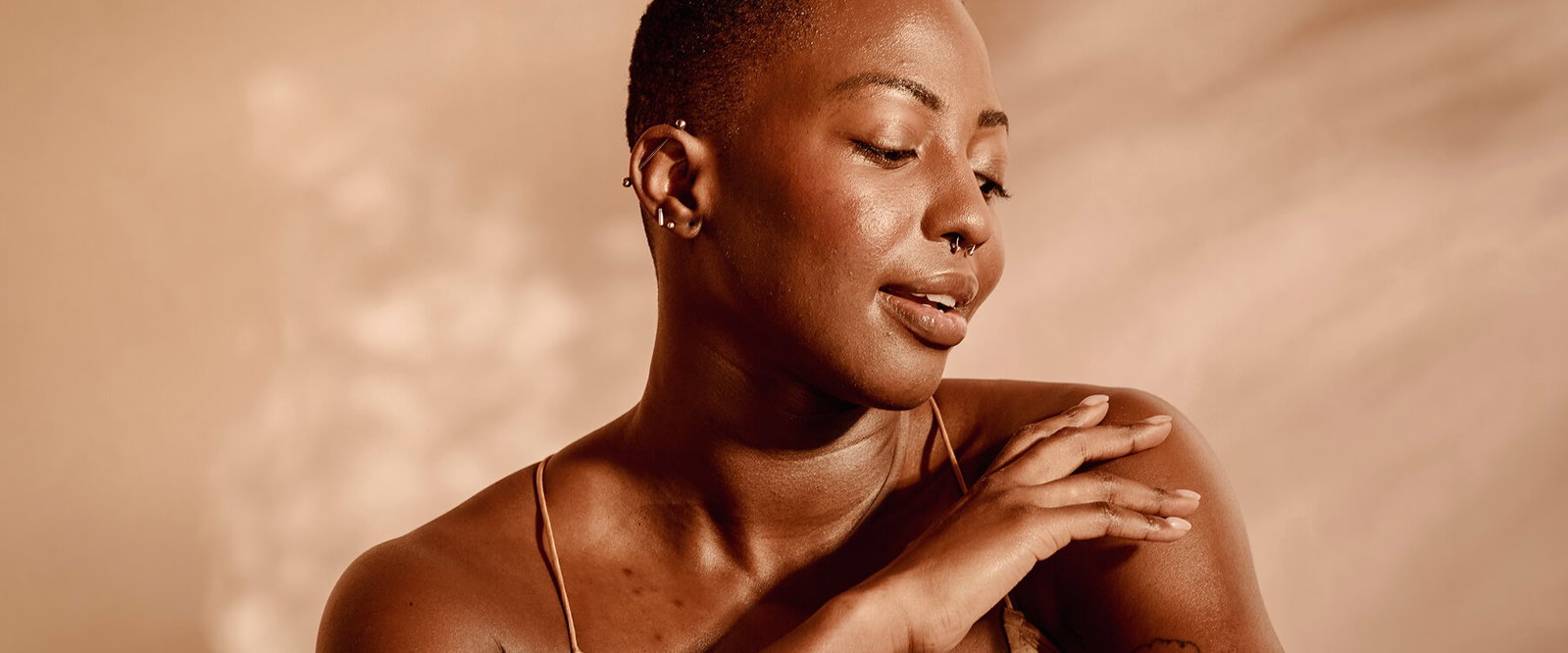 Close-up portrait of a woman with glowing, healthy skin against a warm neutral background