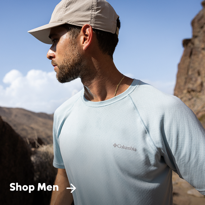 Man outside on rocky terrain wearing Columbia hat and shirt. 