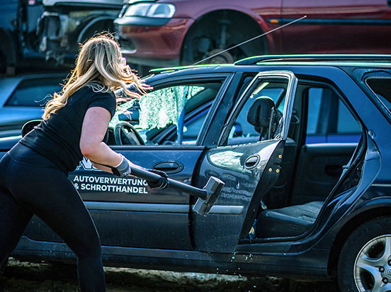 Frau schlägt auf ein Auto mit dem Hammer ein