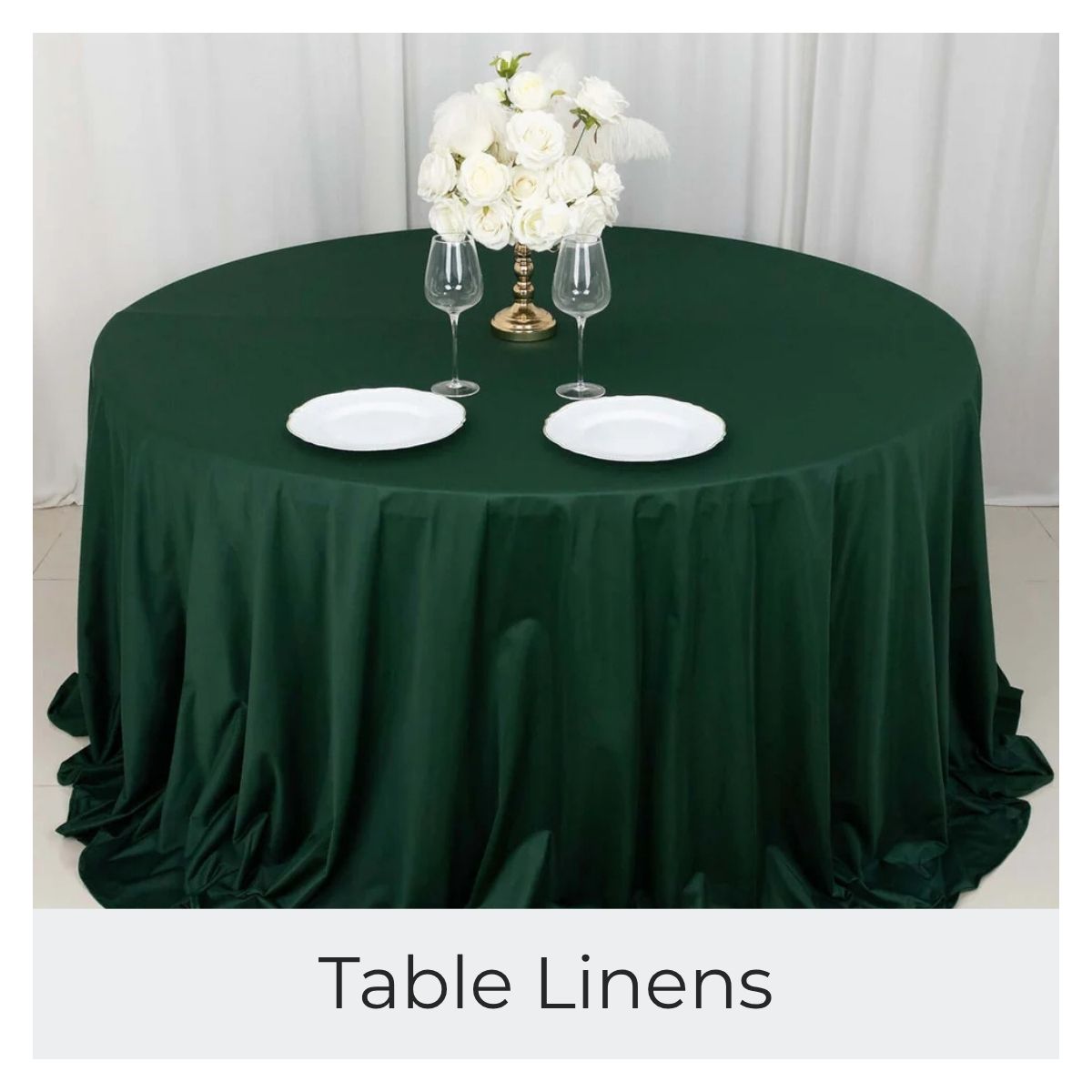 A round white tablecloth covers a table set with plates and wine glasses.