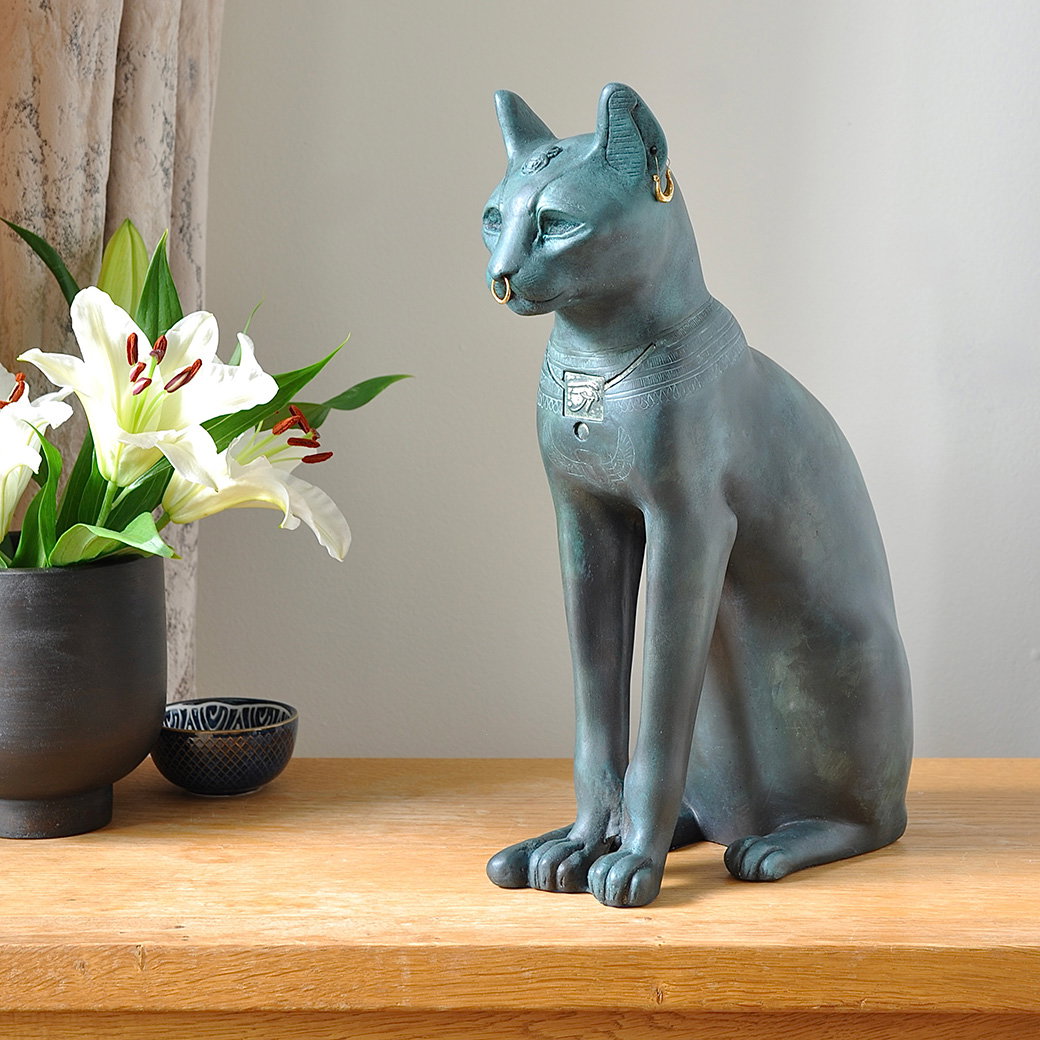 Finely crafted replica of the ancient Egyptian Gayer-Anderson Cat statue with rich green-blue patination, darkened bronze-effect tones and gold-coloured jewellery details. - Shop Now.