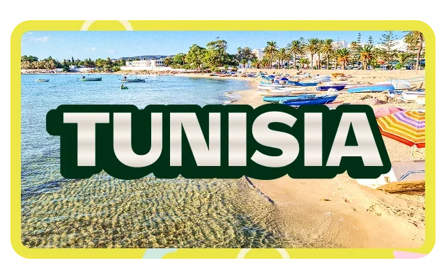 Bright yellow border with geometric pattern, 'TUNISIA' dark green bold text with white outline, clear turquoise-blue shallow water, sandy rippled bottom, small boats, beige-tan sand, colourful beach umbrellas, blue white orange striped, beach loungers, palm trees, low-rise buildings and clear blue sky.