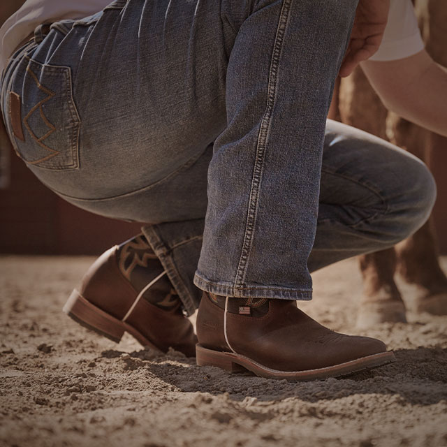 A cowboy wearing the Long western boots in brown.