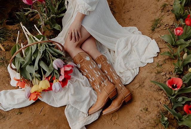 A woman wearing the May 15" Western boots in  Antique Tan.
