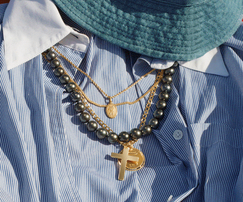 Rotating frames of layered necklaces with shirt and hat, being worn by male model in pool, and a dish of men’s jewelry.
