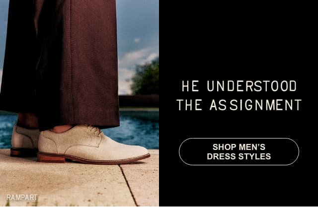 A split image. On the left, a close-up photo shows a person wearing beige "RAMPART" dress shoes and dark trousers. On the right, a solid black block features white text reading: "HE UNDERSTOOD THE ASSIGNMENT" with a button underneath that says "SHOP MEN'S DRESS STYLES".