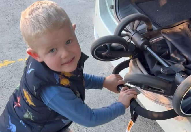 A child putting a stroller into a car boot