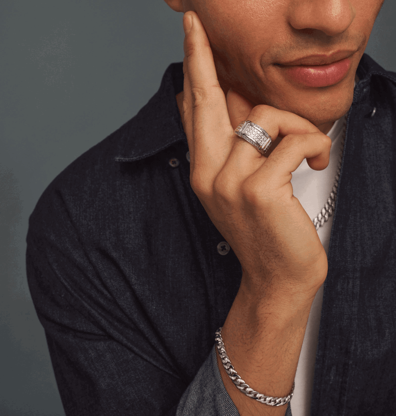 Man wearing a multi-row diamond ring, silver chain bracelet and chain necklace.