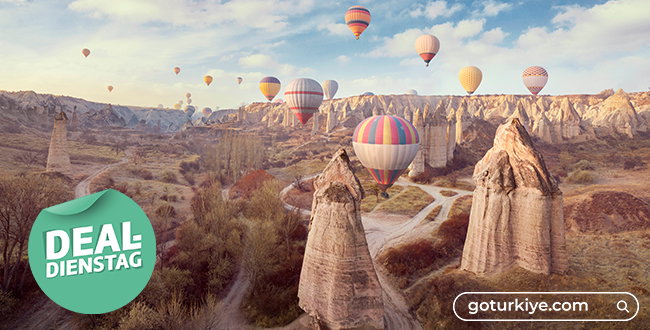 Landschaft von Kappadokien mit Heißluftballons am Himmel und Steinkegeln.