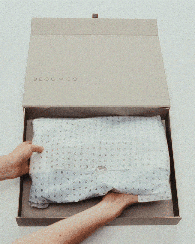 hands placing tissue wrapped gift in a box and finishing with a ribbon