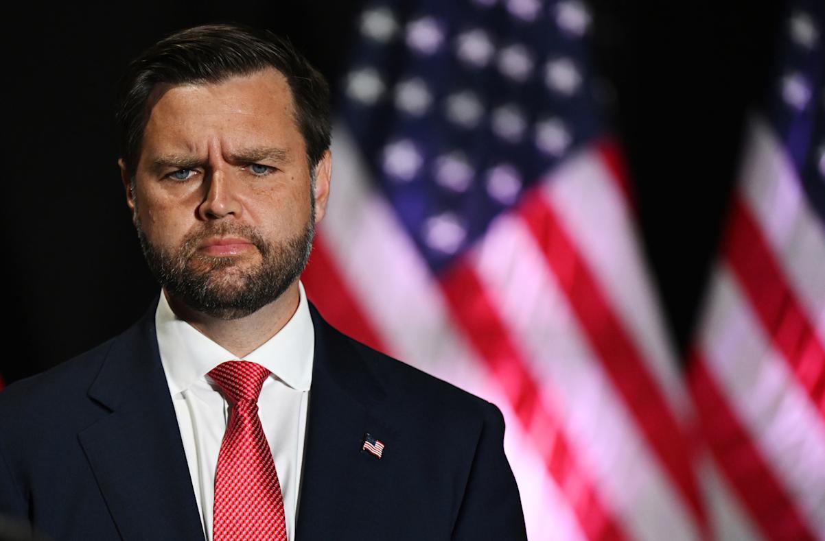 JD Vance standing in front of American flags