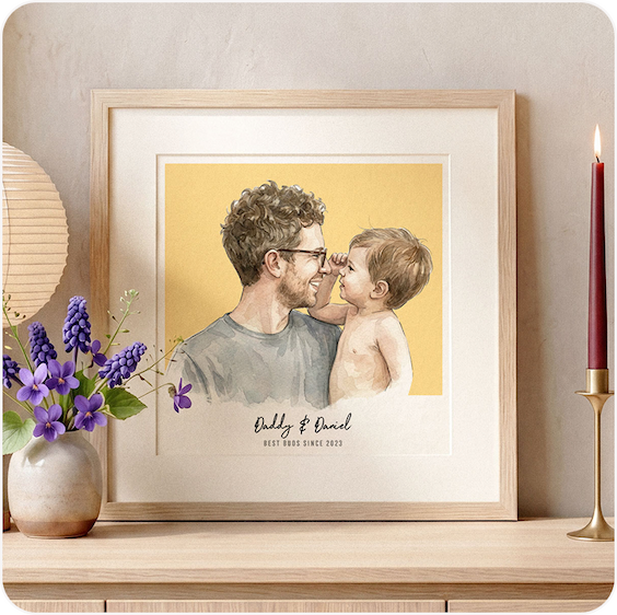 A framed watercolour illustration of a father and baby touching noses, personalised with "Daddy & Daniel, best buds since 2023", displayed on a shelf with purple flowers and a candle