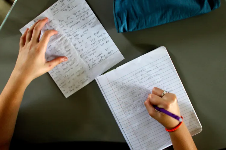 A 6th-grade student takes notes during an English class