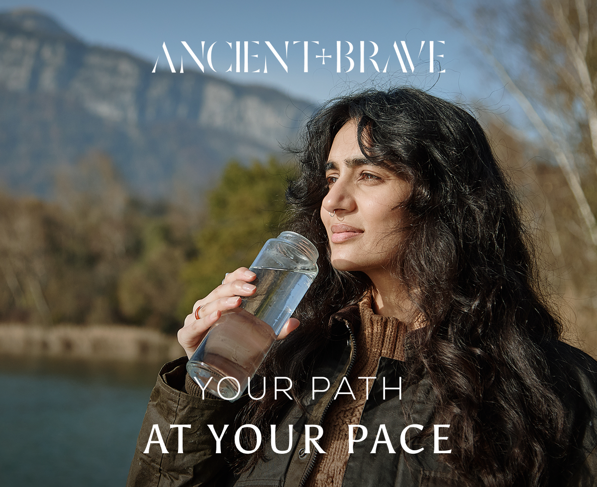 Woman lifting a water bottle to her mouth against a mountain backdrop, with Ancient + Brave logo and the words 'Your path at your pace' overlaid.