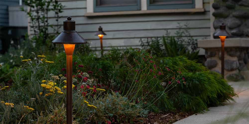 A series of illuminated pathway lights in a garden.