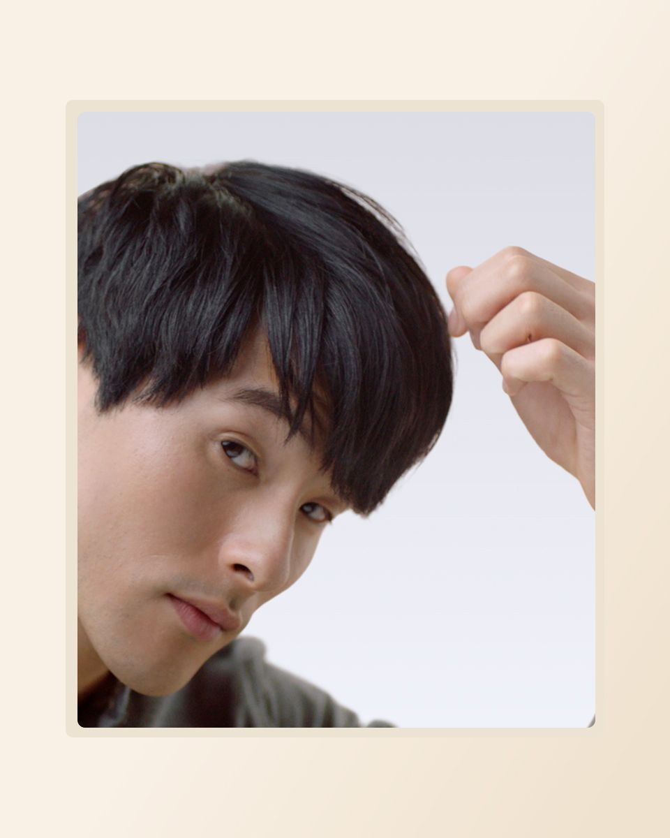 Model applies the finishing touches to his short hair style after using the Dyson Supersonic hair dryer.