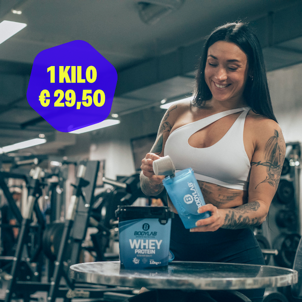 an image of a woman drinking water while standing in a gym