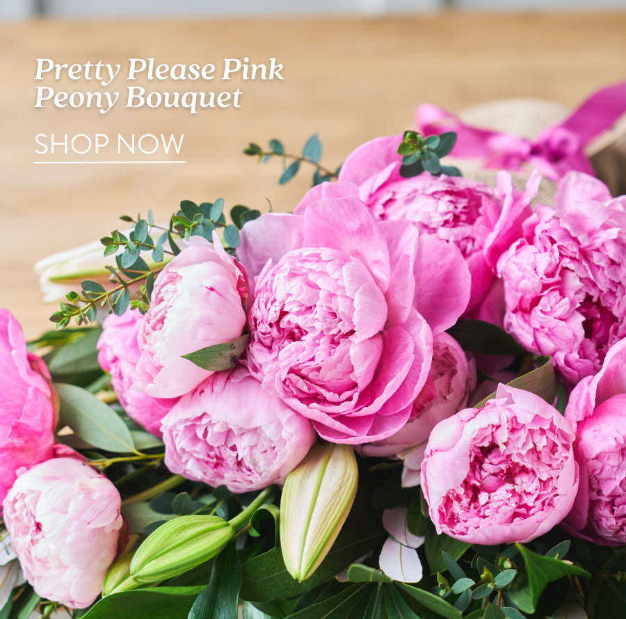 Close-up of a lush pink peony bouquet with eucalyptus on a wood surface. Text reads: Pretty Please Pink Peony Bouquet. Shop Now.