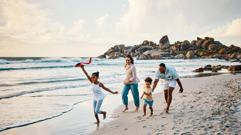 A mother, father and their two kids playing on a beach.