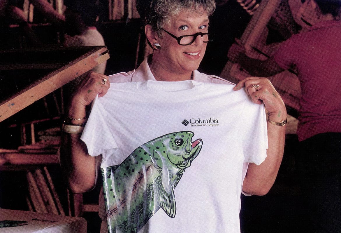 Archival image of Gert Boyle holding a graphic tee with a fish on it