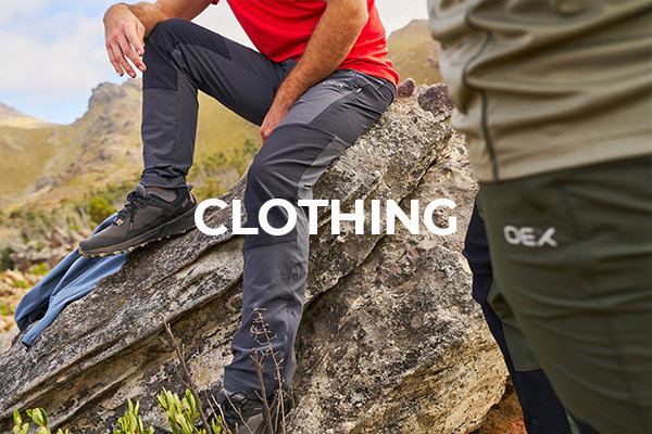 Two models wear OEX hiking pants, one in green and the other in grey, one sits on a rock.