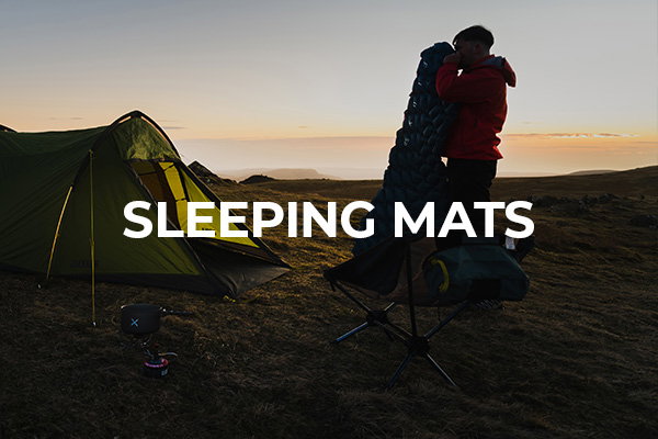 Camper blows up his OEX sleeping mat while the sun sets on the horizon.