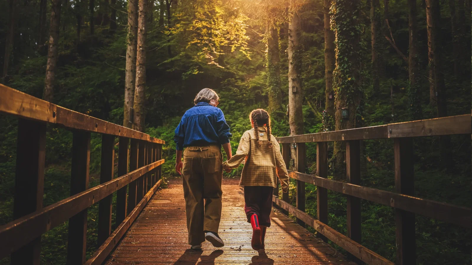 Grandmother and daughter walking across a bridge at sunset in Bluestone's woodland