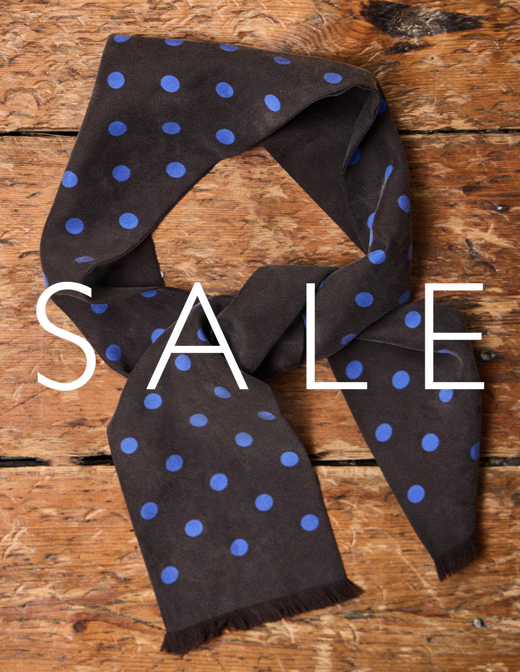 Sale: navy polka dot scarf arranged on a rustic wooden surface