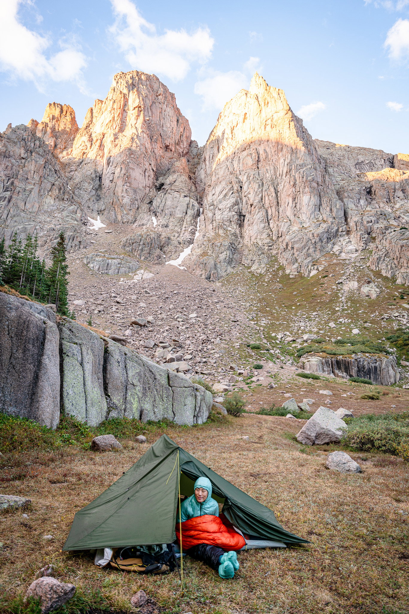 Girl sitting in tent with mountain behind them