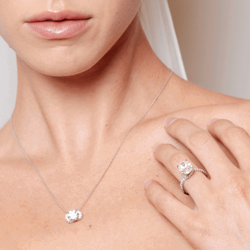 Bride wearing a diamond pendant necklace and engagement ring. 