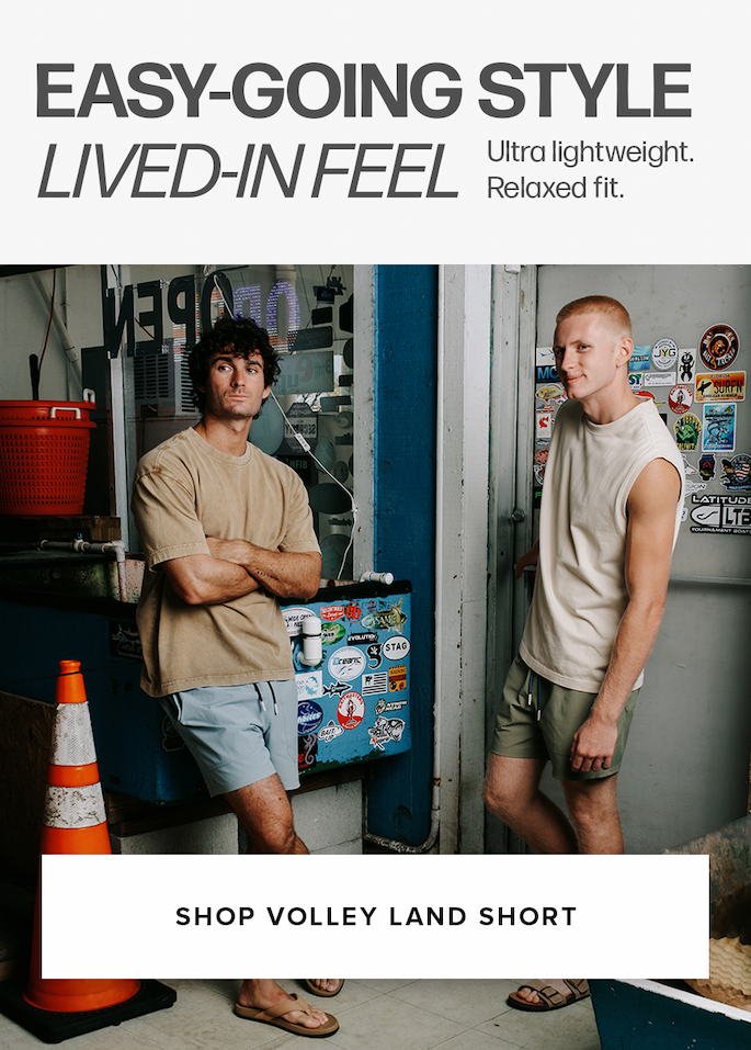 Two men stand by a door in tan and cream tops with blue and green shorts. Text reads: 'Easy-Going Style Lived-In Feel Ultra lightweight. Relaxed fit. Shop Volley Land Short'