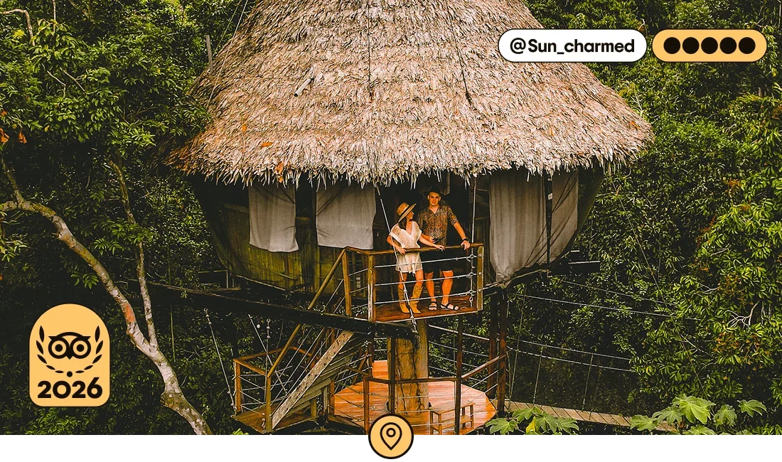 Image description: Two travelers standing on the terrace of a thatch-roofed room surrounded by jungle, photo taken by @Sun_charmed