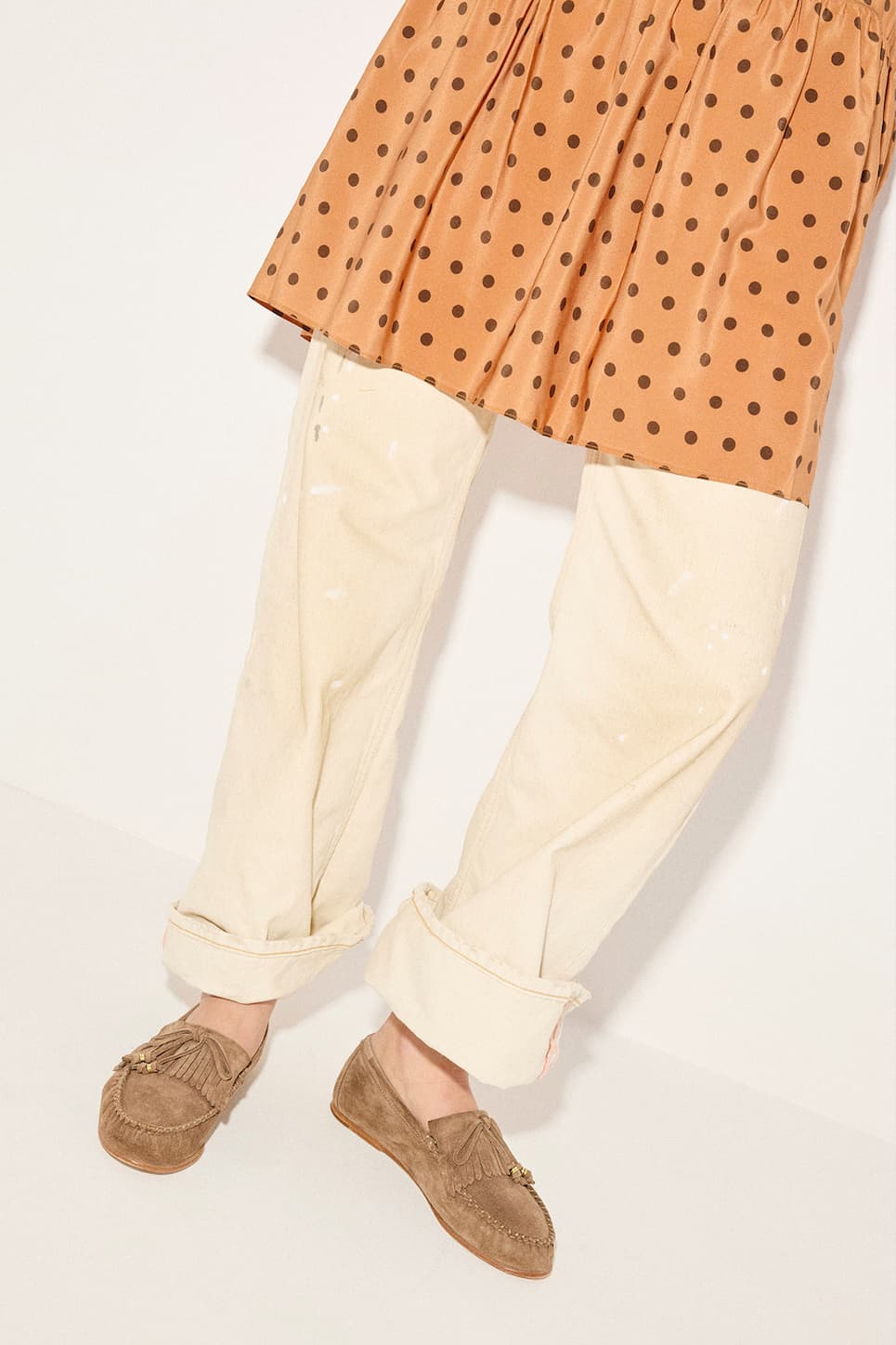 woman in orange skirt with brown dots over khaki cuffed pants wearing brown suede loafers