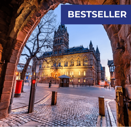 View of a historic building illuminated at dusk, framed by an archway and cobblestone street.