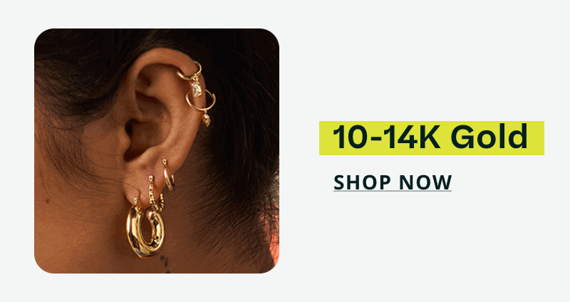 Ear styled with various gold hoops, including thick huggies & dainty gold charms on cartilage. 10-14K gold. Click here to shop now