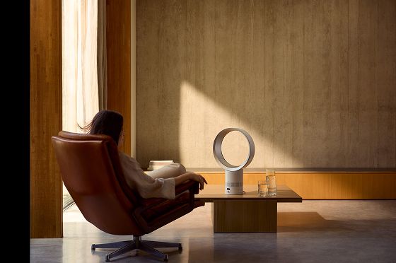 A person enjoying the comfort of a Dyson fan near a bright window.