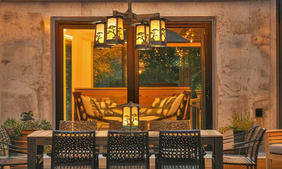 The outdoor dining area of a vintage home with a chandelier and cordless lamp.