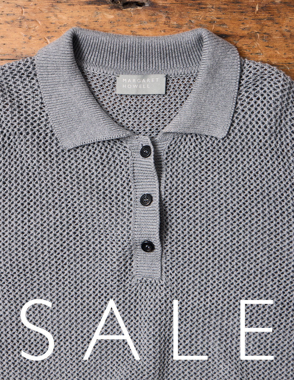 Sale now on: textured grey knit polo styled on a wooden surface