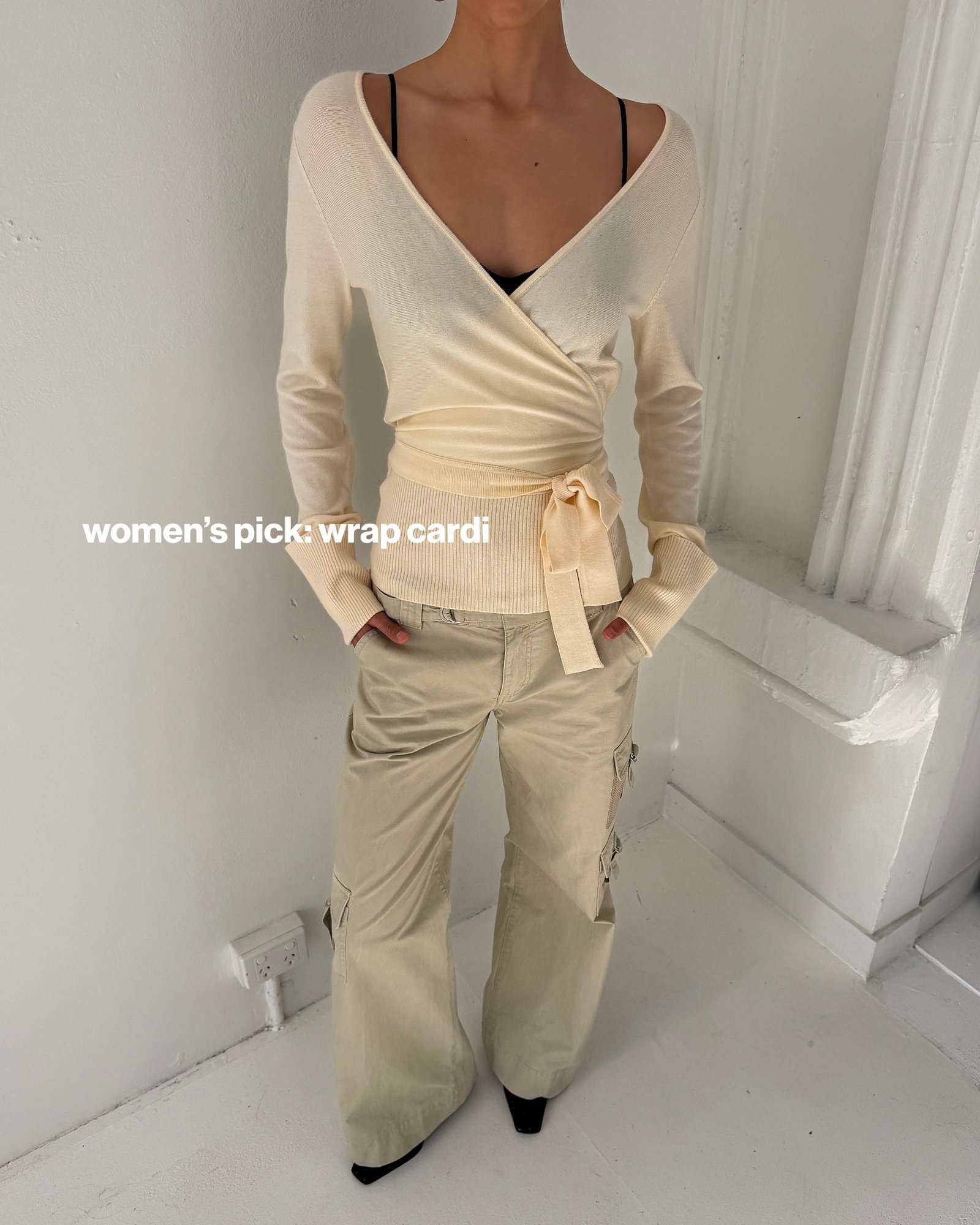 A medium shot shows a person wearing a cream-colored wrap cardigan with a black bra underneath, paired with loose-fitting beige cargo pants, and the t...