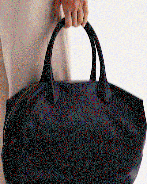 GIF of a model in a neutral outfit carrying a chocolate brown bag.