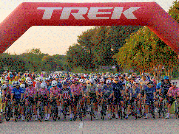 Cyclists crossing the Trek 100 finish line