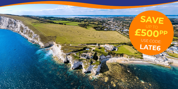 Aerial view of a coastal landscape featuring cliffs, green fields, and a blue sea.