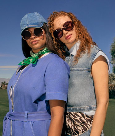 Two people stood wearing sunglasses and casual outfits against a blue sky.