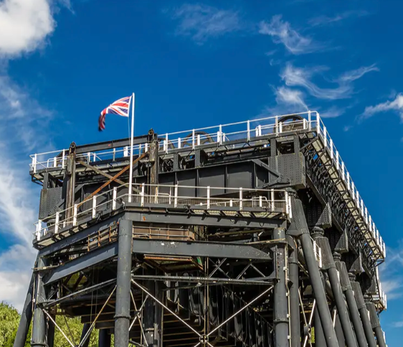 Industrial structure with a Union Jack flag against a blue sky and wispy clouds.