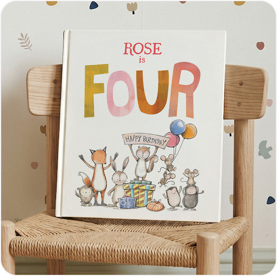 A personalised birthday book titled "Rose is Four" displayed on a wooden chair