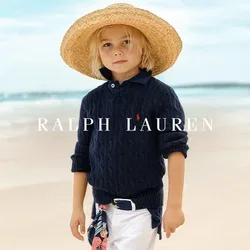 Marine-blaues Kabelstrickpullover, weiße hochgekrempelte Hosen und ein großer Strohhut. Ausgestattet mit einem blumengemusterten Schal, der um die Taille gebunden ist.