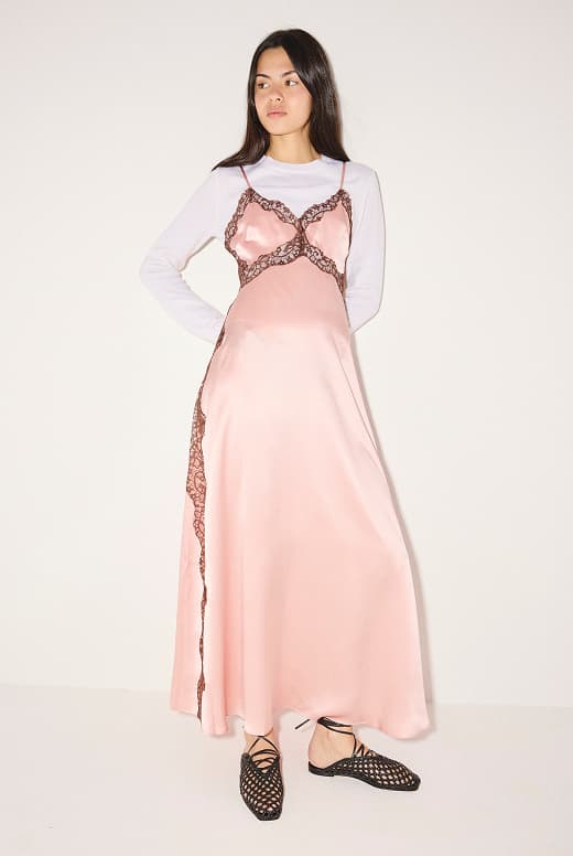 woman standing in pink silk dress with black woven slides with ankle ties