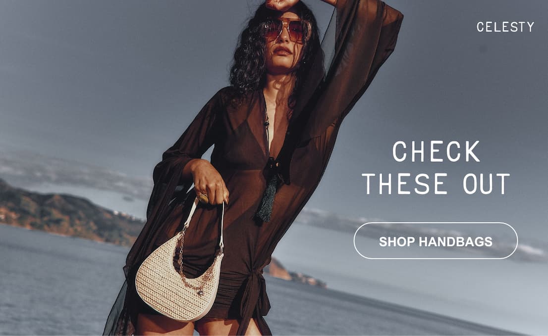 A banner image featuring a model outdoors in a dark dress, holding a cream raffia handbag with gold charms. Text on the right reads "CHECK THESE OUT" above a button that says "SHOP HANDBAGS".