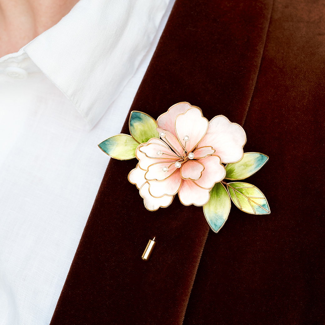 Peony brooch crafted from embroidered pink and green silk, pinned to a velvet brown jacket. - Shop Now.